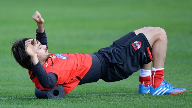 Ein Fußballspieler der österreichischen Nationalmannschaft dehnt seinen Rücken mit einer Faszienrolle.