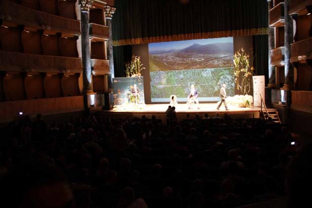 Eine Veranstaltung findet in einem Theater vor einem großen Publikum statt.