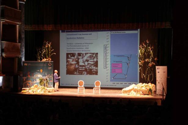 Ein Mann hält einen Vortrag über Röntgenquellen und Synchrotronstrahlung auf einer Bühne.