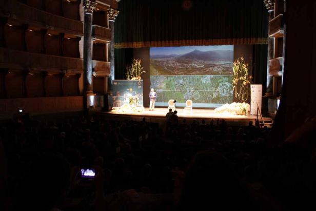 Ein Mann hält eine Präsentation auf einer Bühne vor einem Publikum.