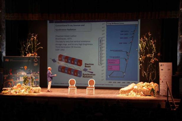 Ein Mann präsentiert auf einer Bühne eine Grafik über Synchrotronstrahlung.