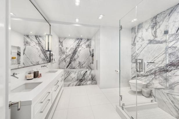 Ein modernes Badezimmer mit Marmorwänden und weißen Armaturen.