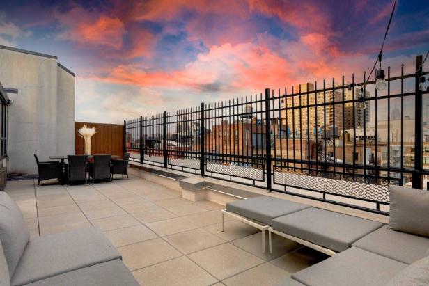 Eine Dachterrasse mit Loungemöbeln und Blick auf die Stadt bei Sonnenuntergang.