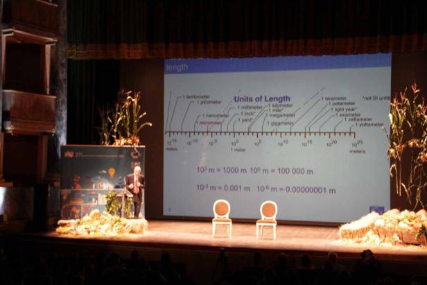 Ein Mann hält eine Präsentation über Längeneinheiten auf einer Bühne.