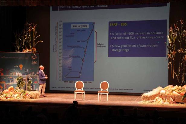 Ein Mann präsentiert auf einer Bühne eine Grafik zur Entwicklung der ESRF-EBS-Technologie.