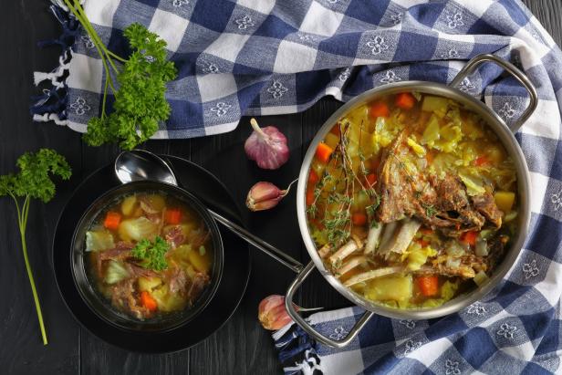 Ein Topf und eine Schüssel mit Kohlsuppe mit Fleisch und Gemüse stehen auf einem Tisch.