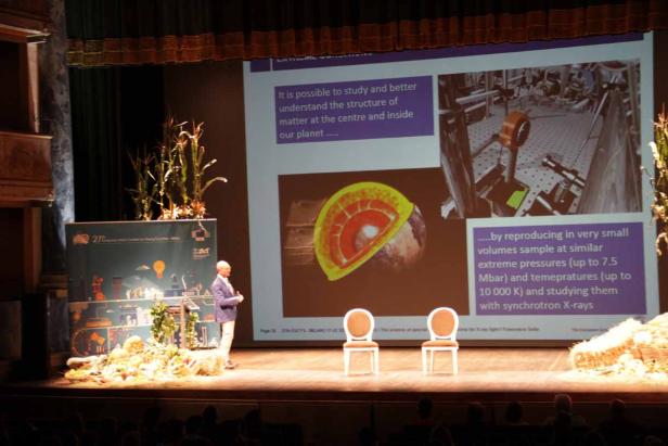 Ein Redner präsentiert eine Grafik über den Aufbau der Erde auf einer Bühne.