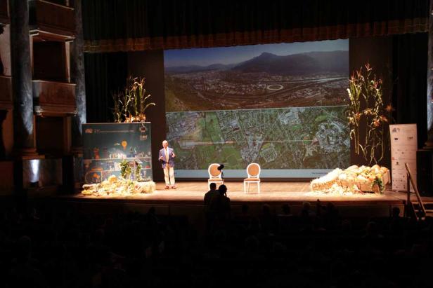 Ein Mann hält eine Präsentation auf einer Bühne vor einem Publikum.