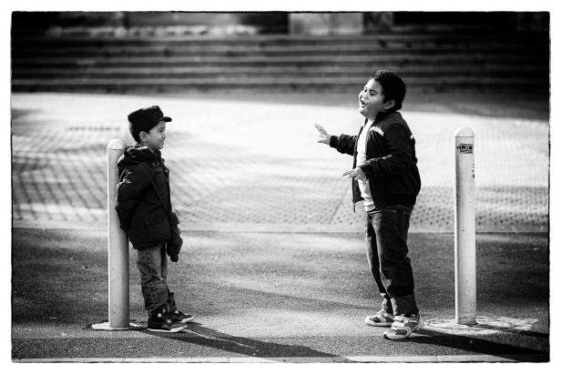 Zwei Jungen stehen sich auf einer Straße gegenüber und gestikulieren.