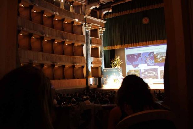 Zuschauer sitzen in einem historischen Theater und sehen sich eine Präsentation an.