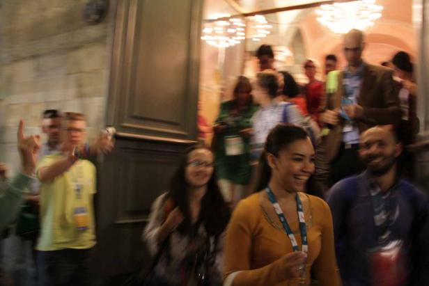 Menschen verlassen ein Gebäude, einige lächeln.