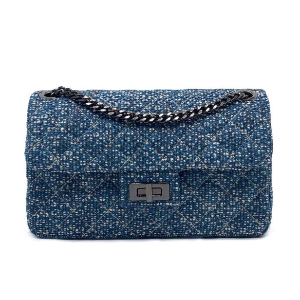 Eine blaue Handtasche mit Kettenriemen vor einem weißen Hintergrund.