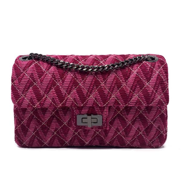 Eine gesteppte, burgunderrote Handtasche mit silberner Kette vor einem weißen Hintergrund.