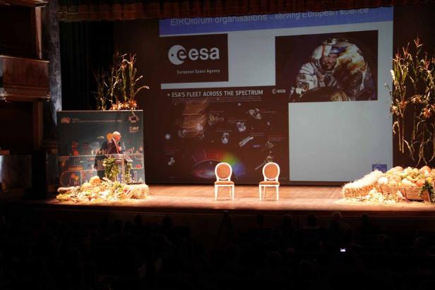 Eine Bühne mit zwei Stühlen, Kürbissen und einer Präsentation der Europäischen Weltraumorganisation ESA.