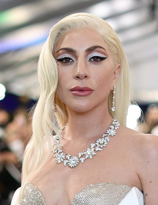 Lady Gaga mit blonden Haaren, auffälligem Make-up und einer Diamantkette.