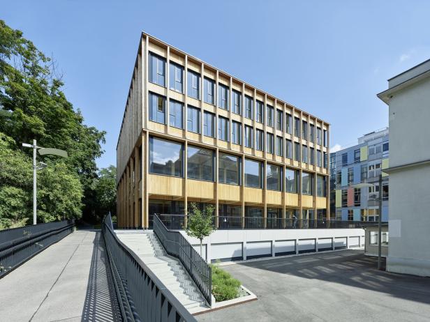Ein modernes, mehrstöckiges Bürogebäude mit Holzfassade und großen Fenstern.