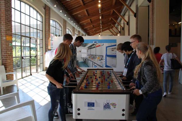 Eine Gruppe von Jugendlichen spielt Tischfußball in einem hellen Raum.