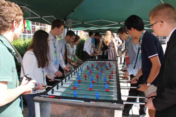 Eine Gruppe von Menschen spielt Tischfußball unter einem grünen Zelt.