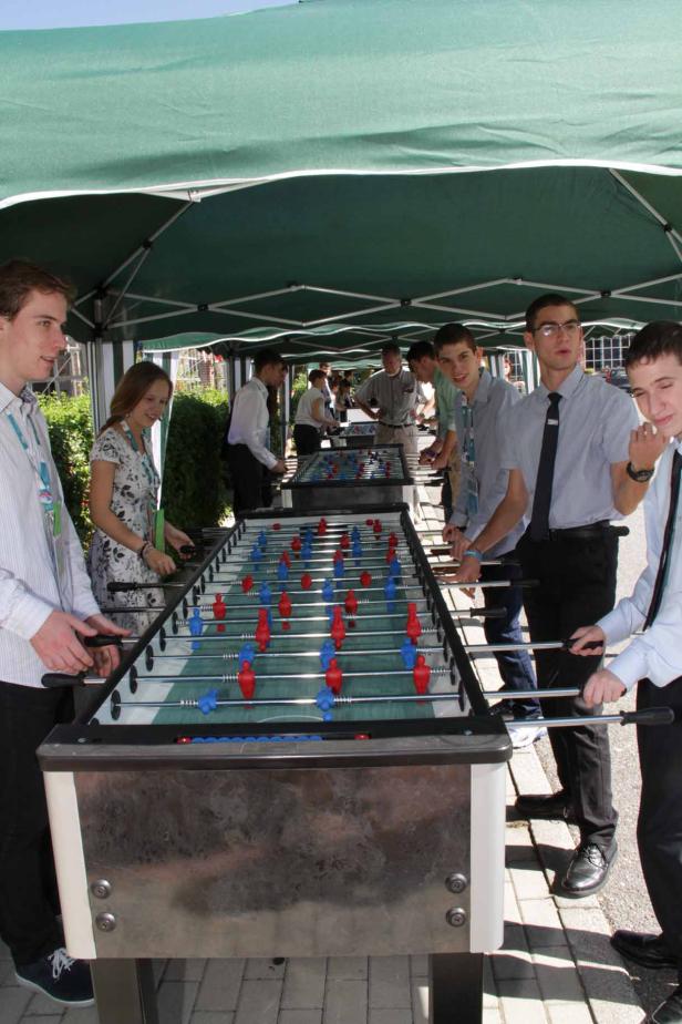 Eine Gruppe von Menschen spielt Tischfußball unter einem grünen Zelt.