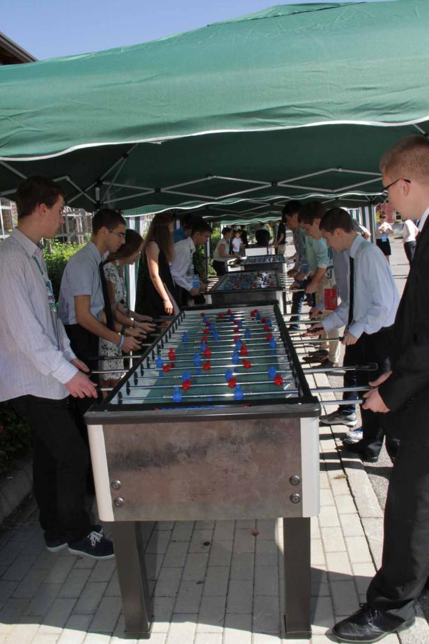Eine Gruppe junger Leute spielt Tischfußball unter einem grünen Zelt.