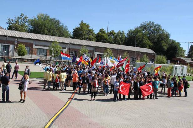 Eine Gruppe von Menschen hält verschiedene Nationalflaggen in die Höhe.
