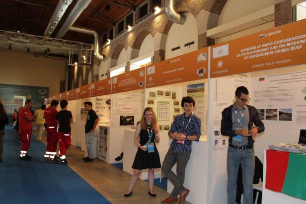 Besucher betrachten Stände auf einer Wissenschaftsmesse mit Postern zu Umweltthemen.