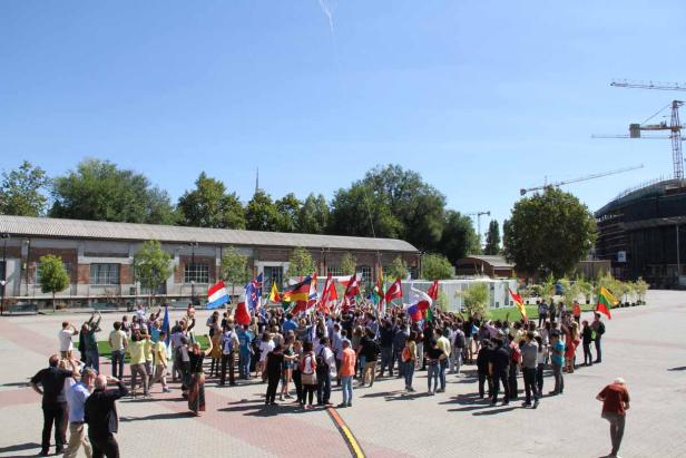 Eine Gruppe von Menschen hält verschiedene Nationalflaggen in die Höhe.
