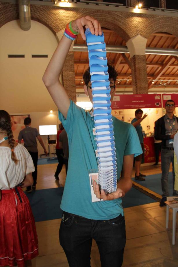 Ein junger Mann hält einen Stapel blauer und weißer Broschüren hoch.