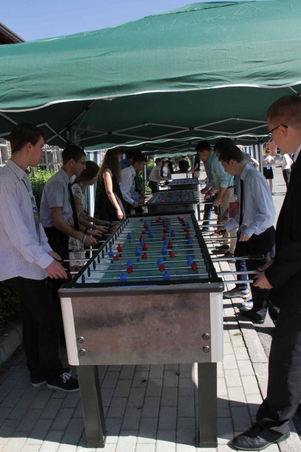 Eine Gruppe junger Leute spielt Tischfußball im Freien.