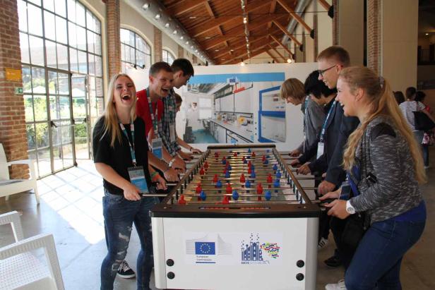 Eine Gruppe junger Leute spielt begeistert Tischfußball.