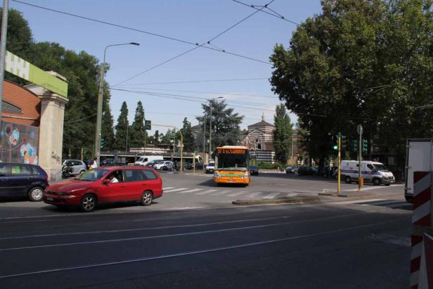 Ein gelber Bus fährt über eine Kreuzung in einer italienischen Stadt.