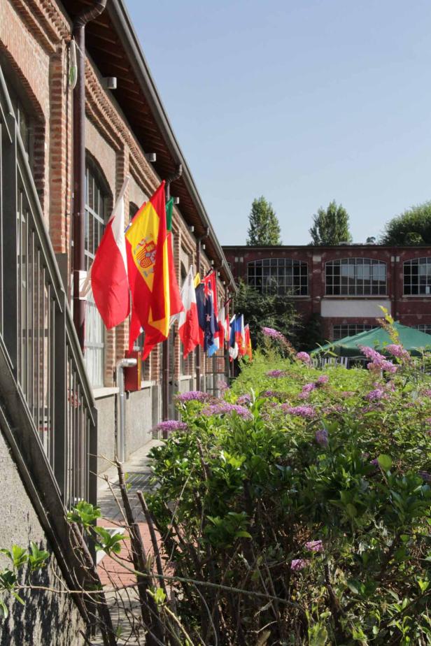 An einem Backsteingebäude hängen verschiedene Nationalflaggen.