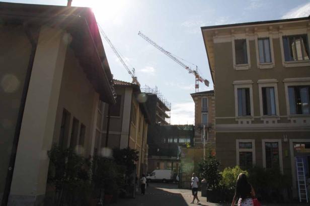 Zwei Baukräne ragen über die Gebäude einer Stadt.