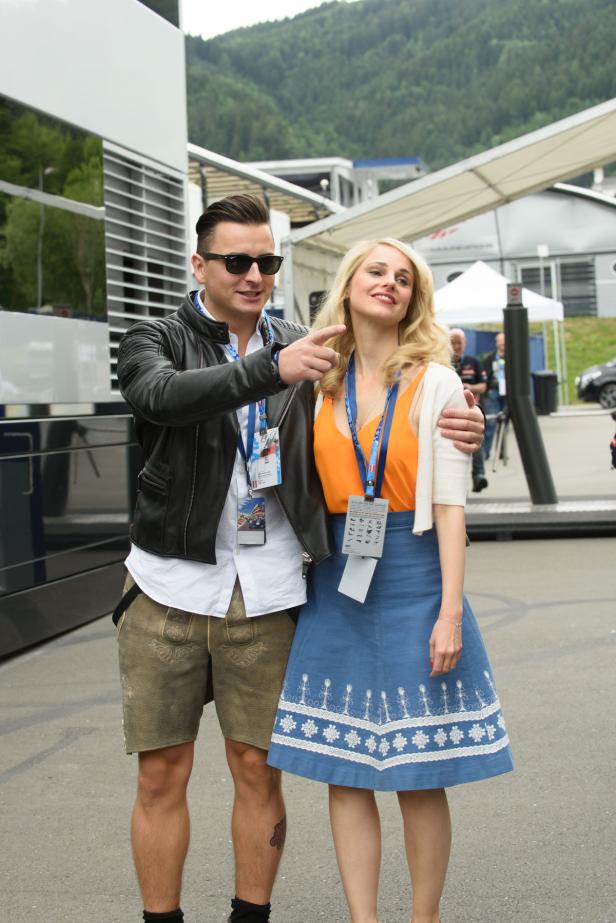 Ein Mann in Lederhosen und eine Frau in einem Dirndl stehen zusammen im Freien.