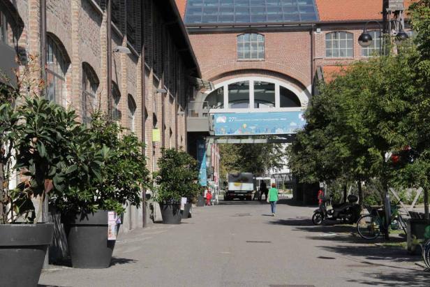 Eine Frau geht auf einem Platz zwischen Backsteingebäuden hindurch.