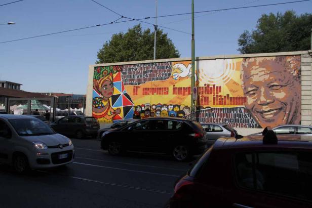 Ein großes Wandgemälde mit dem Porträt von Nelson Mandela und anderen Motiven in einer Stadt.