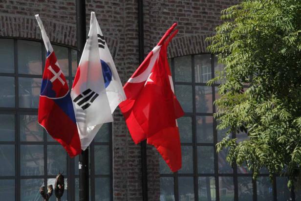 Die Flaggen der Slowakei, Südkoreas und der Türkei wehen vor einem Gebäude.