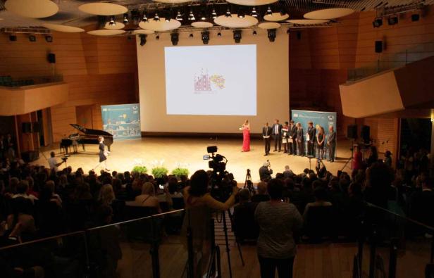 Eine Preisverleihung findet in einem Konzertsaal vor Publikum statt.