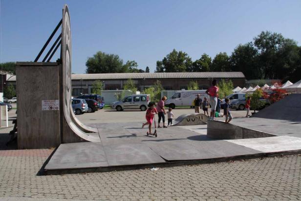 Kinder spielen auf einem Skatepark mit Rampen und Hindernissen.