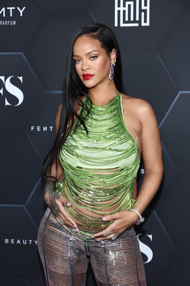 Rihanna posiert in einem grünen Oberteil und einer glitzernden Hose auf einem Event.