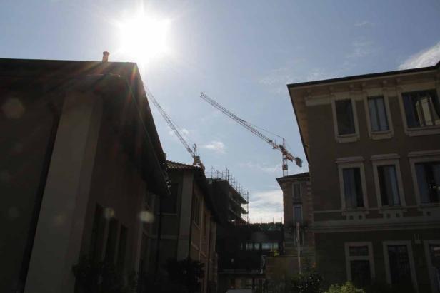 Zwei Baukräne ragen zwischen Wohnhäusern in den Himmel.