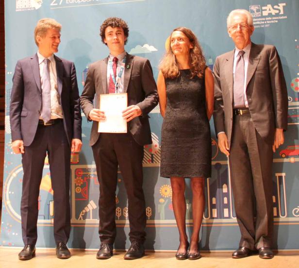 Vier Personen posieren vor einem Banner bei einer Preisverleihung.