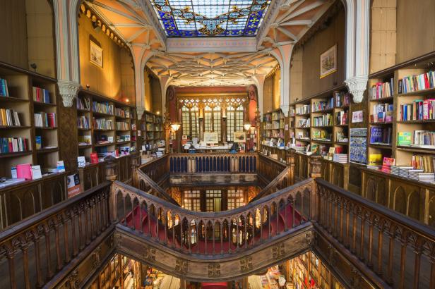 Blick in die prachtvolle Buchhandlung Livraria Lello in Porto mit geschwungenen Treppen und Bücherregalen.