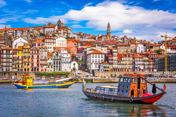 Blick auf die bunten Häuser von Porto, Portugal, mit traditionellen Booten auf dem Douro-Fluss.