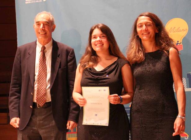 Barbara Roos erhält eine Auszeichnung, flankiert von zwei Personen.