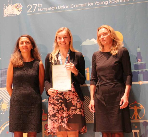 Drei Frauen posieren vor einem Banner des 27. Europäischen Wettbewerbs für junge Wissenschaftler.