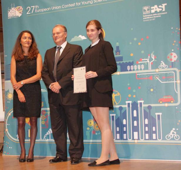 Drei Personen stehen vor einem Banner des 27. Europäischen Wettbewerbs für junge Wissenschaftler.