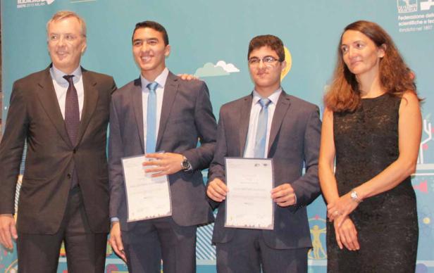 Zwei junge Männer mit Urkunden, flankiert von einem Mann und einer Frau.