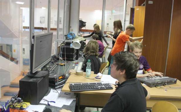 Eine Gruppe von Jugendlichen arbeitet an einem Mischpult in einem Raum.