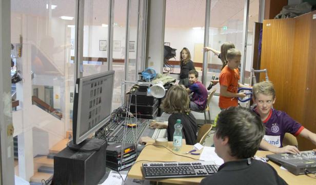 Eine Gruppe von Kindern arbeitet an einem Mischpult in einem Tonstudio.